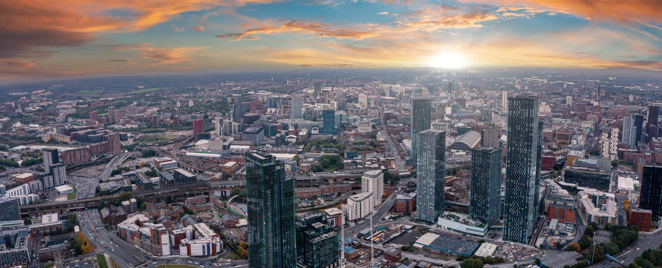 Aerial view of Manchester city centre at sunset, with the Deansgate Square towers and the arched roof of Manchester Central